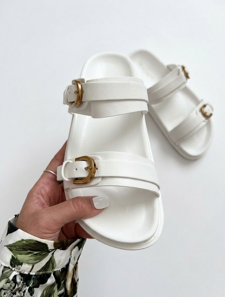 White women’s platform slide sandals with double straps and gold-tone buckle detailing.