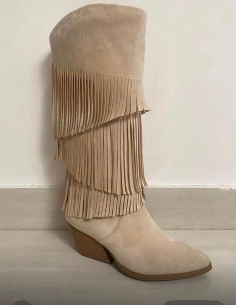 Women's beige suede knee-high Western boots featuring layered fringe detailing and a low stacked heel.