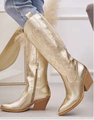 Women's metallic gold knee-high Western cowboy boots with pointed toe and block heel.